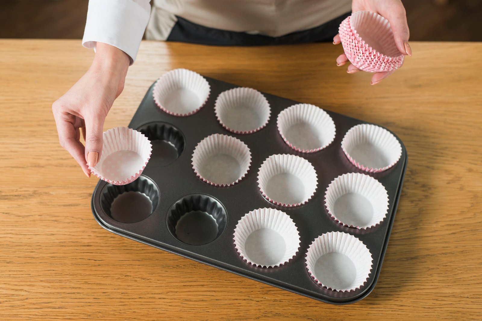 overhead view woman s hand arranging cupcake holder baking tray wooden table scaled