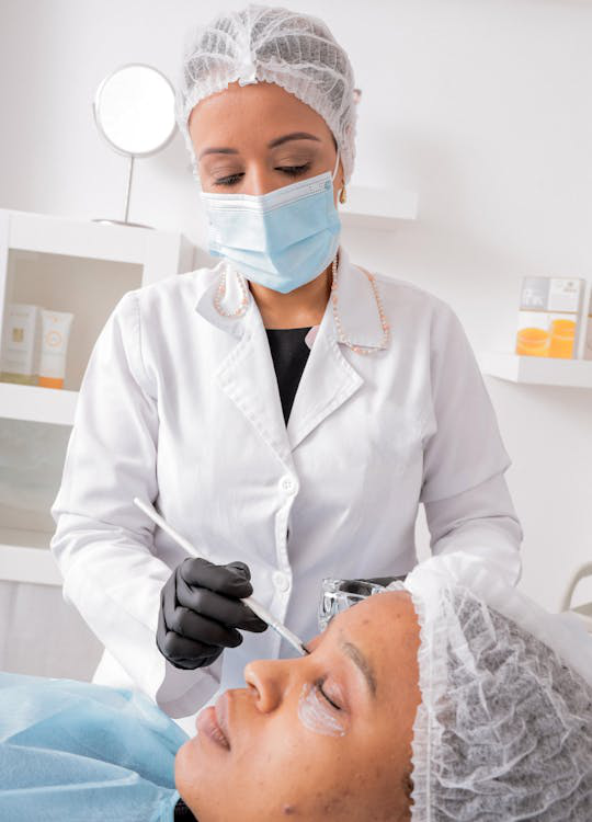 A cosmetic surgeon performing a treatment on a patient’s face