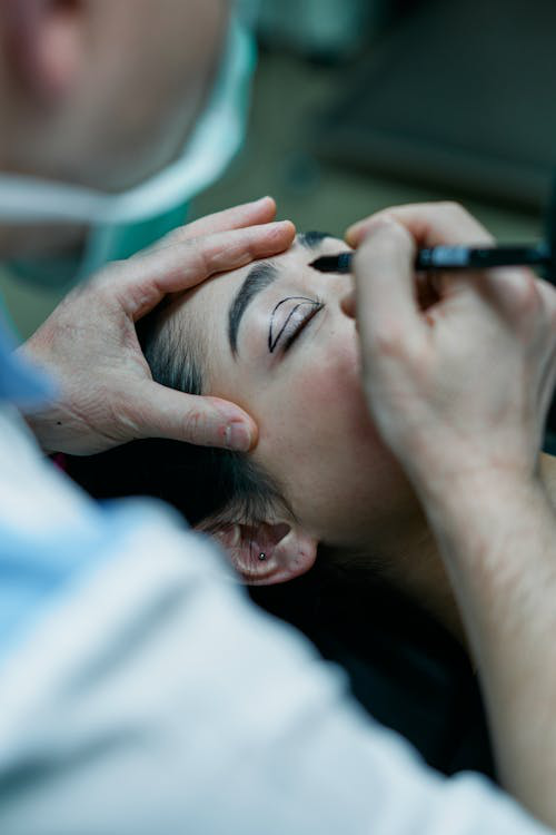 A surgeon mapping a patient’s eyelid for blepharoplasty