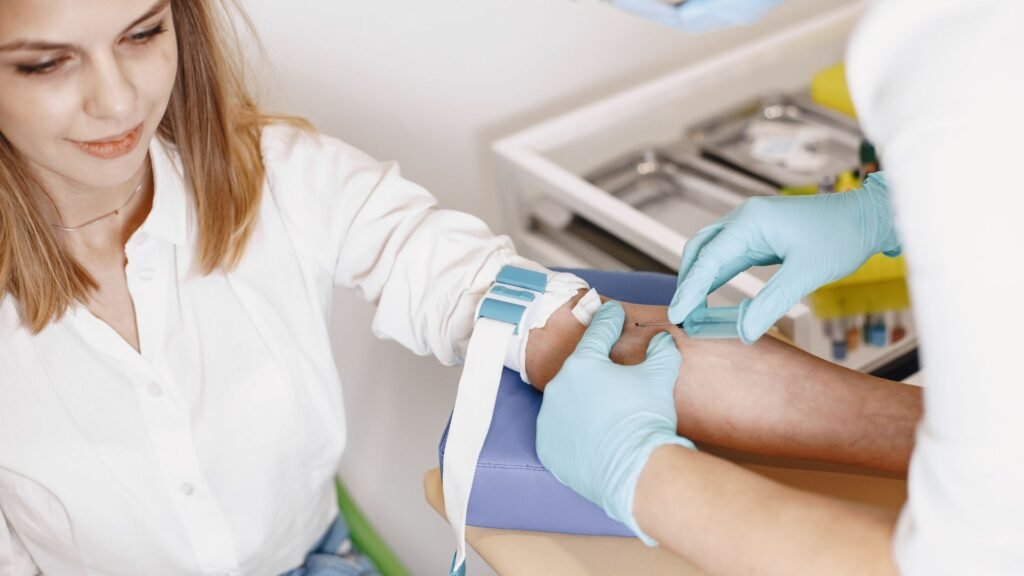 Nurse drawing blood from a smiling female patient during a medical check-up, using a tourniquet and sterile gloves.